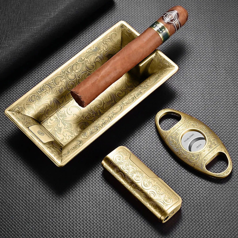 Cigar with a gold humidor, cutter, and lighter on a dark textured surface