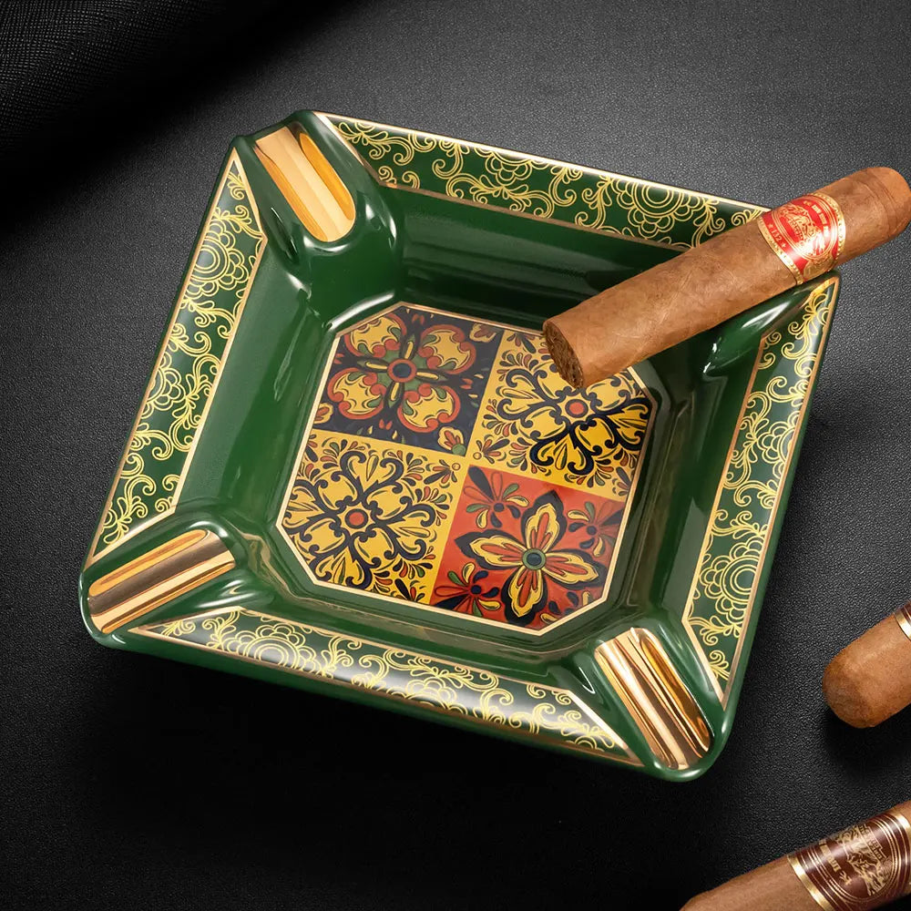 Decorative green ashtray with floral patterns and a cigar on a dark background