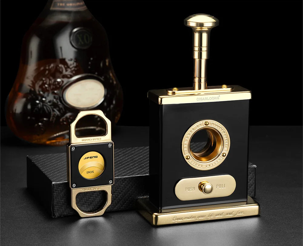 Black and gold desktop cigar cutter and guillotine cutter on a dark background.