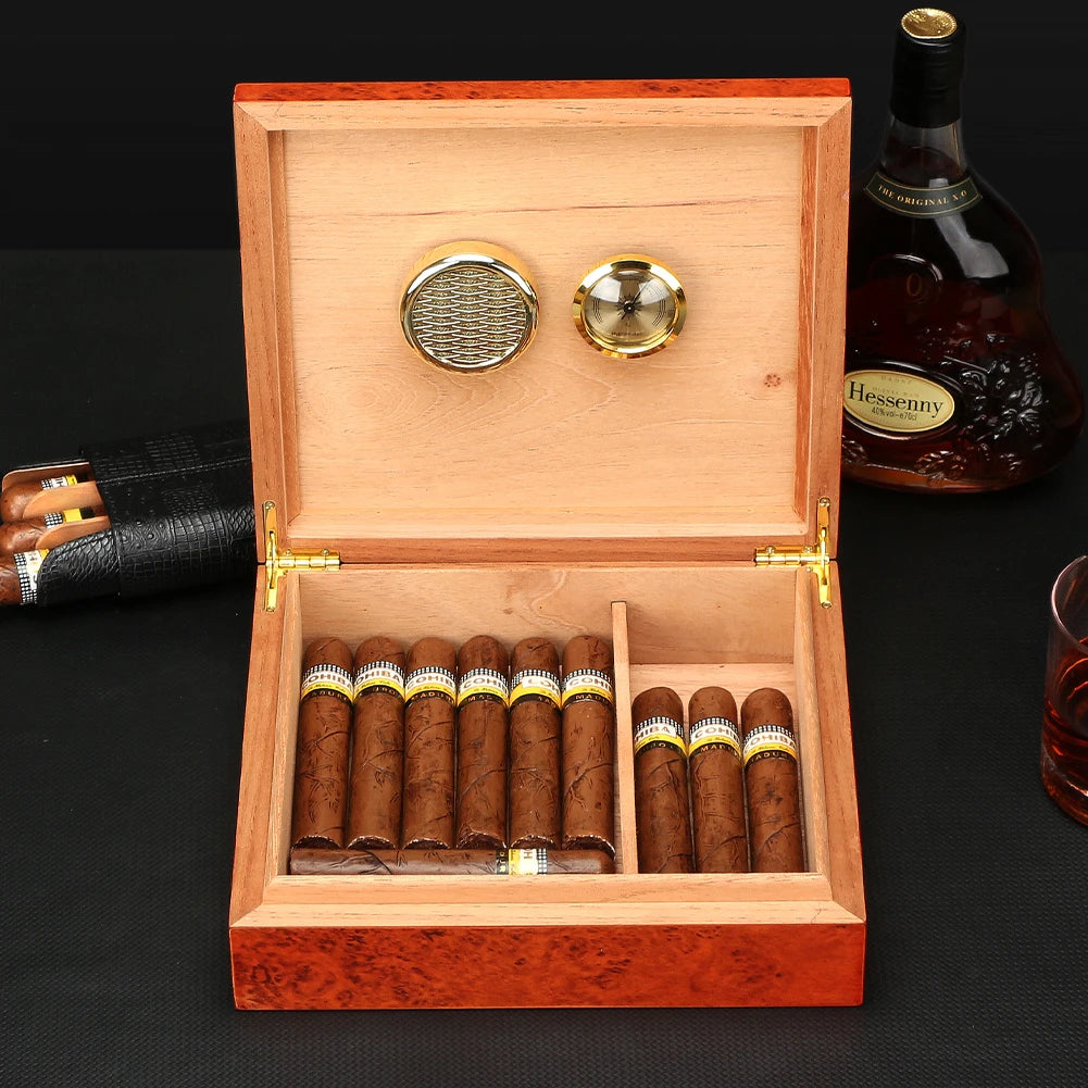 Open wooden humidor with cigars, a bottle of Heskeny whiskey, and a glass on a dark surface.