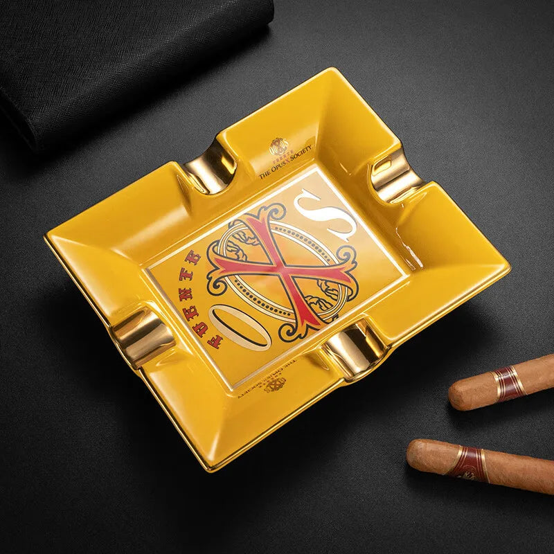 Yellow ashtray with a decorative opusX design on a black surface