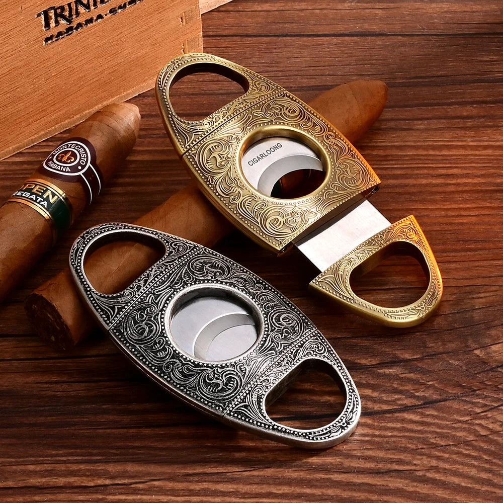 Two ornate cigar cutters on a wooden surface with cigars.