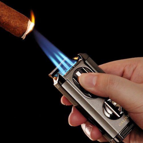 Hand holding a butane lighter igniting a lit cigar against a black background