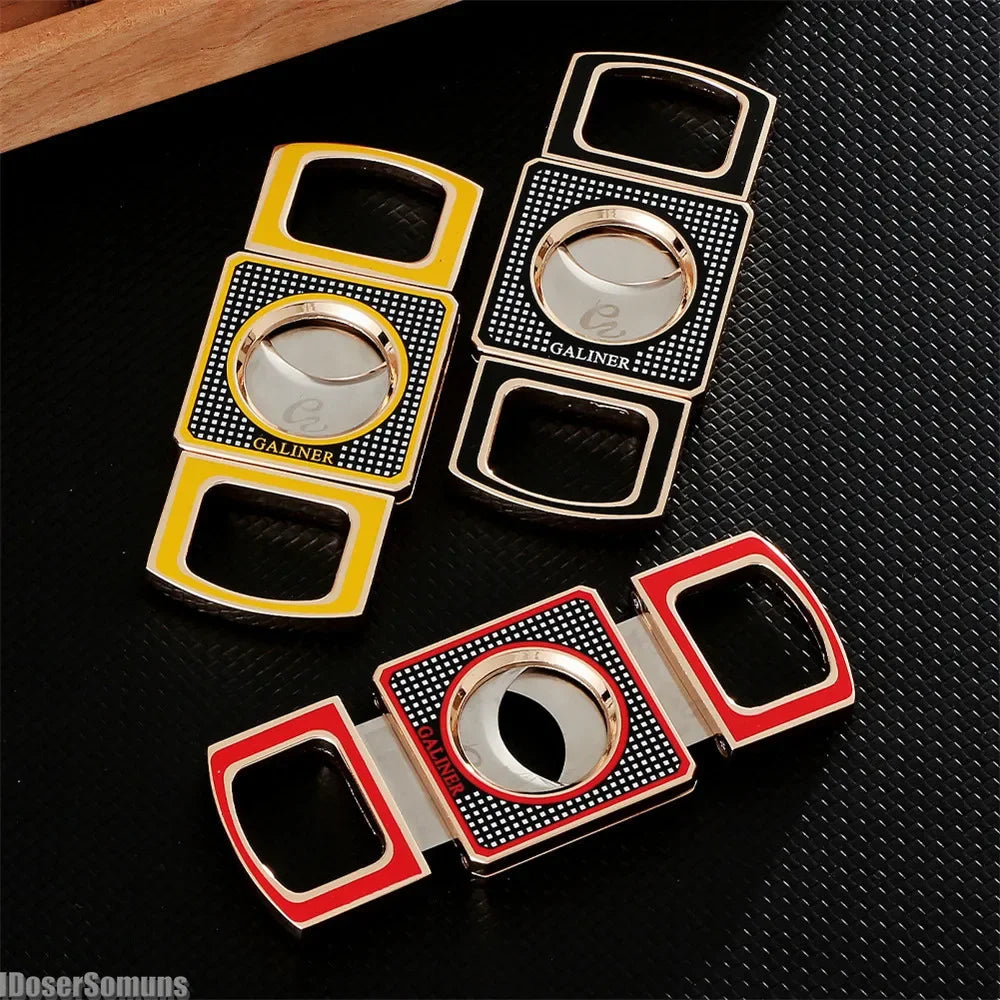 Three cigar cutters with different colored frames on a black textured surface.