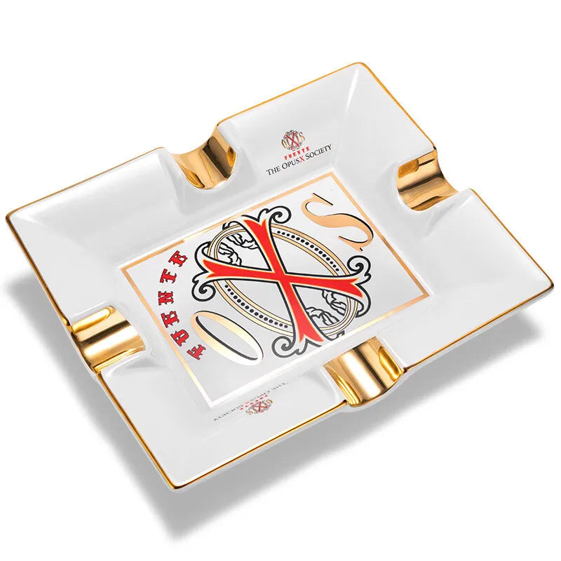 Opus X  white ashtray with gold accents and a logo on a white background