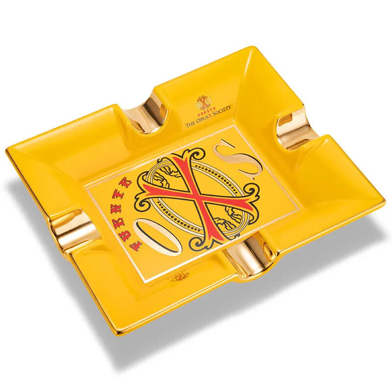 Yellow ashtray with Opus X emblem with gold accents on on a white background